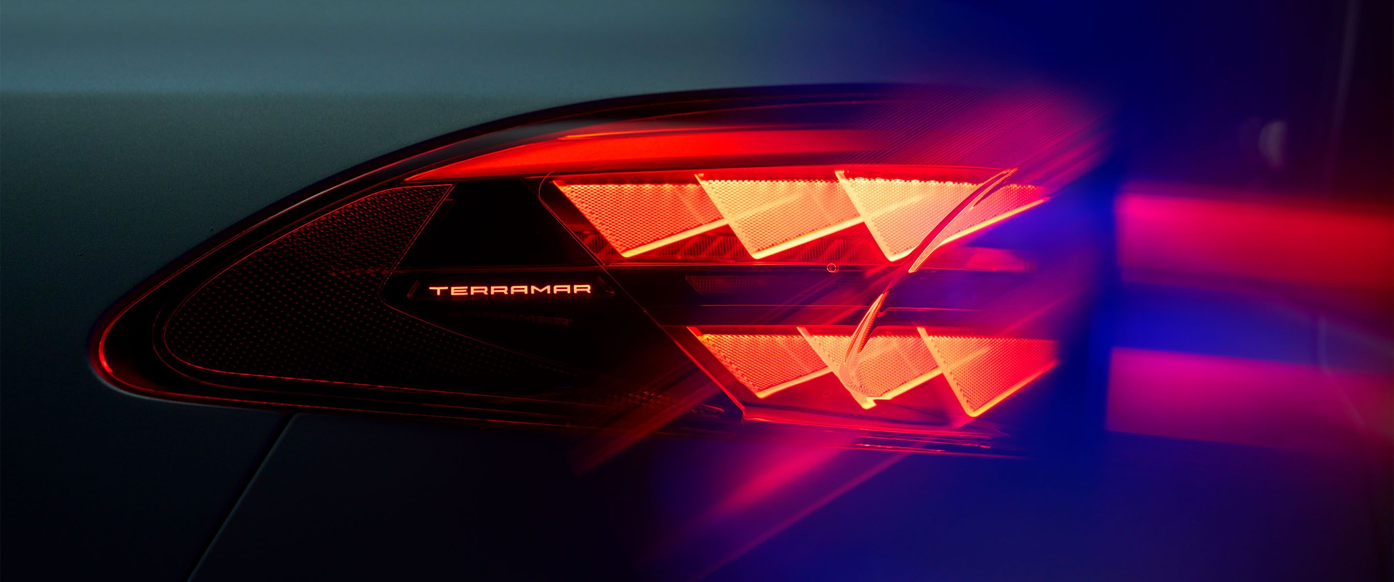 Cupra Terramar : gros plan du feu arrière avec le nom du modèle éclairé, montrant le motif lumineux triangulaire rouge distinctif sur fond sombre.