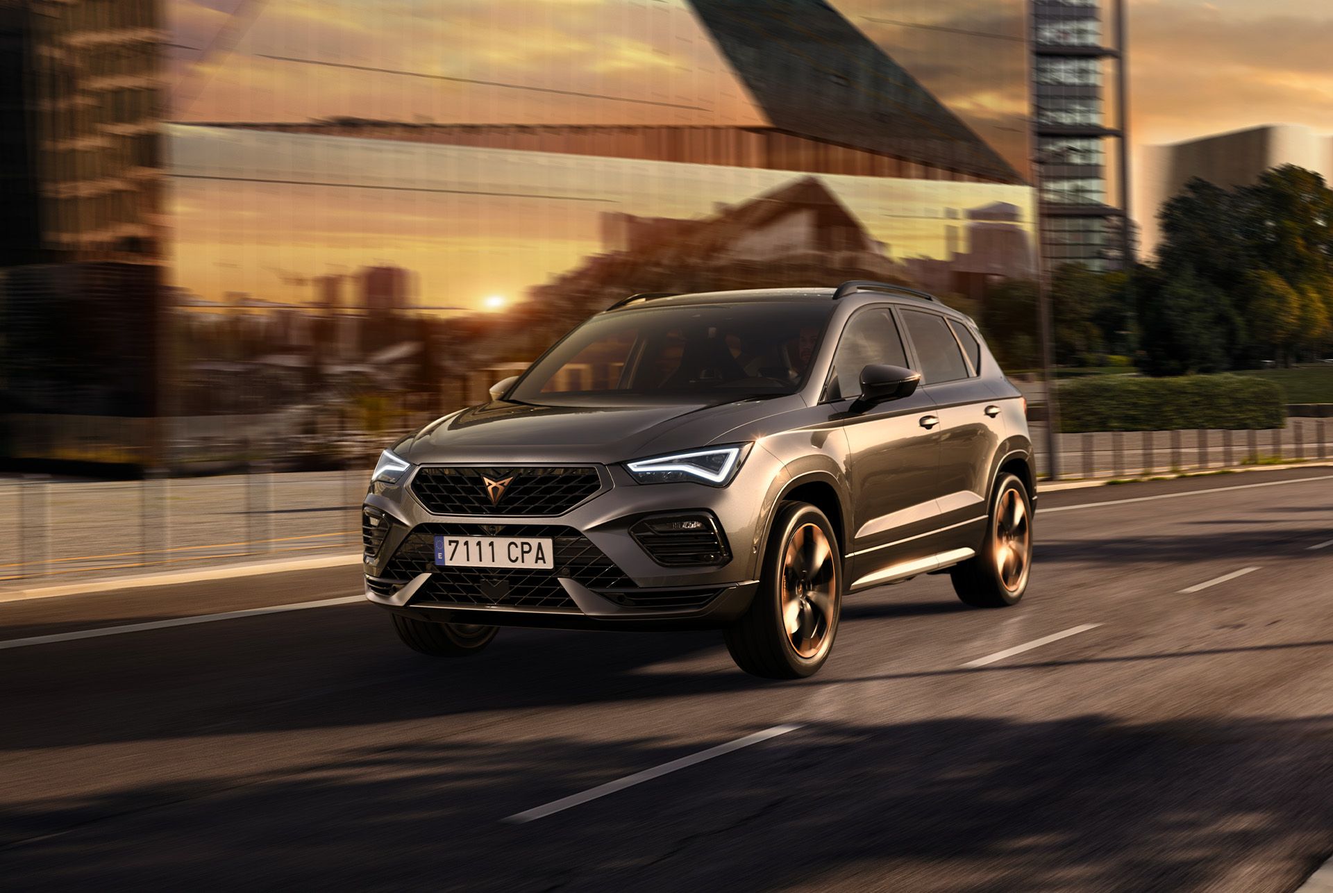 CUPRA Ateca SUV fährt auf einer Stadtstrasse bei Sonnenuntergang. Der SUV ist mit 190 PS und 300 PS starken Motoren mit Allradantrieb erhältlich, die für weniger Emissionen und einen geringeren Kraftstoffverbrauch sorgen.