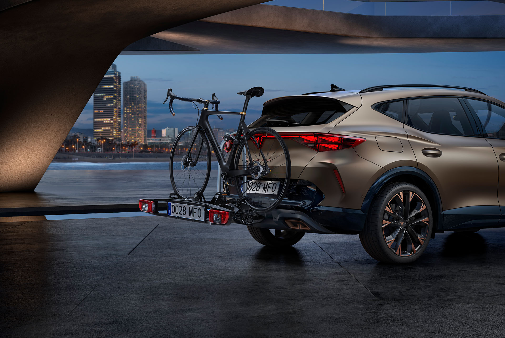 New century bronze CUPRA Formentor 2024 rear and towing bike rack car accessory, city skyline in the background.