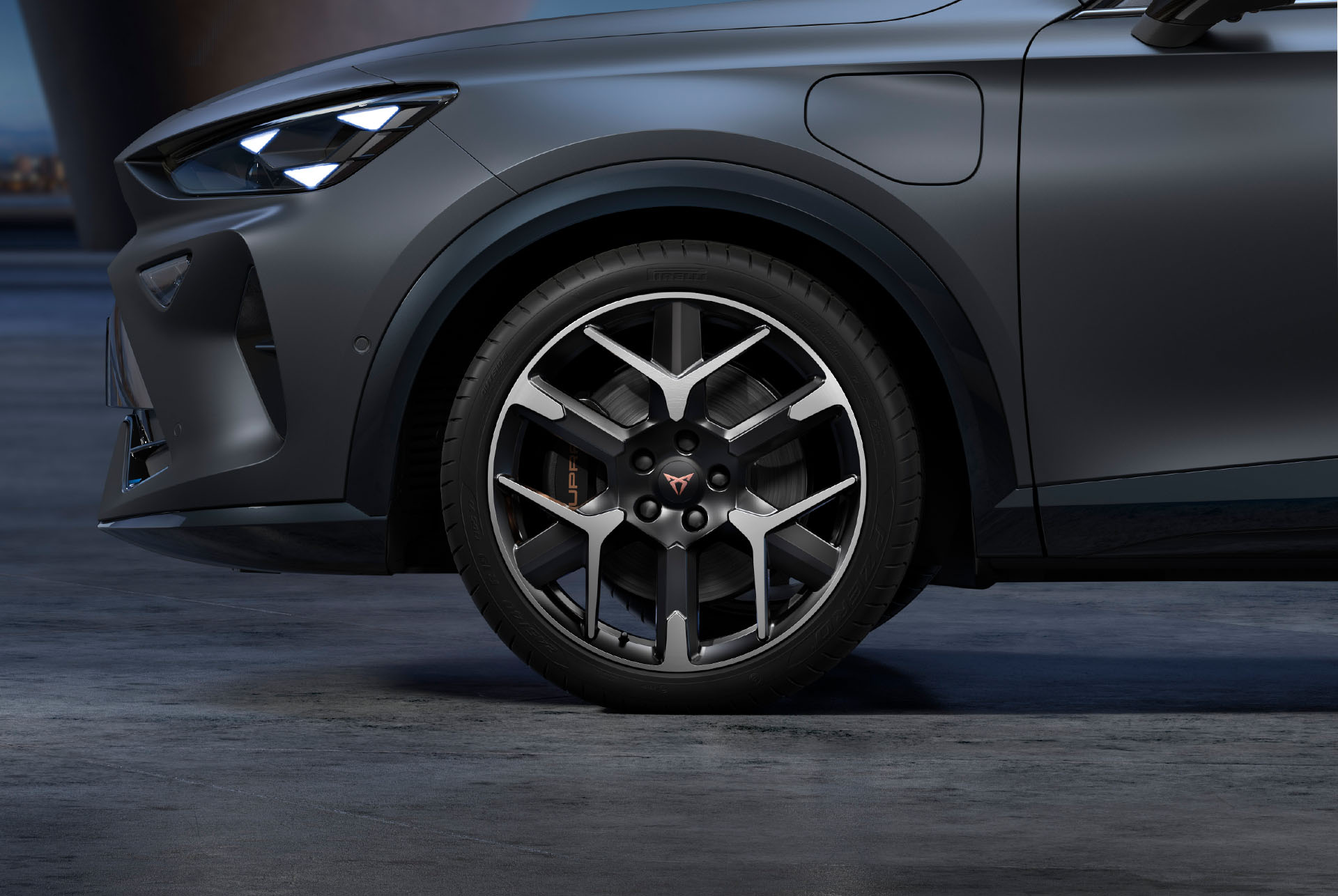 Vordere Seitenansicht der schwarz-silbernen Schmiedefelgen links, Reifen und typische Scheinwerferform.