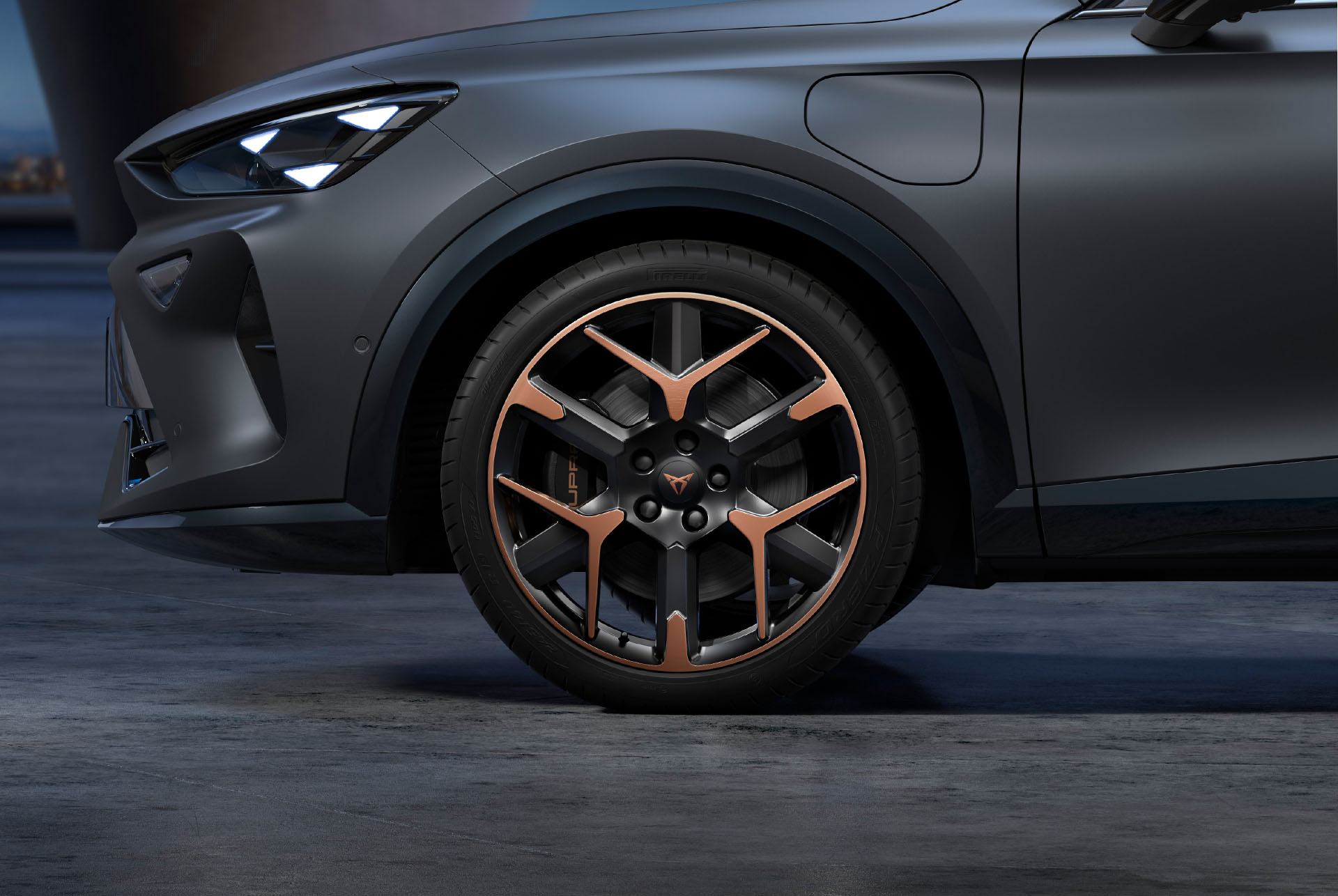 Vordere Seitenansicht der schwarz-kupferfarbenen Schmiedefelgen links, Reifen und typische Scheinwerferform.