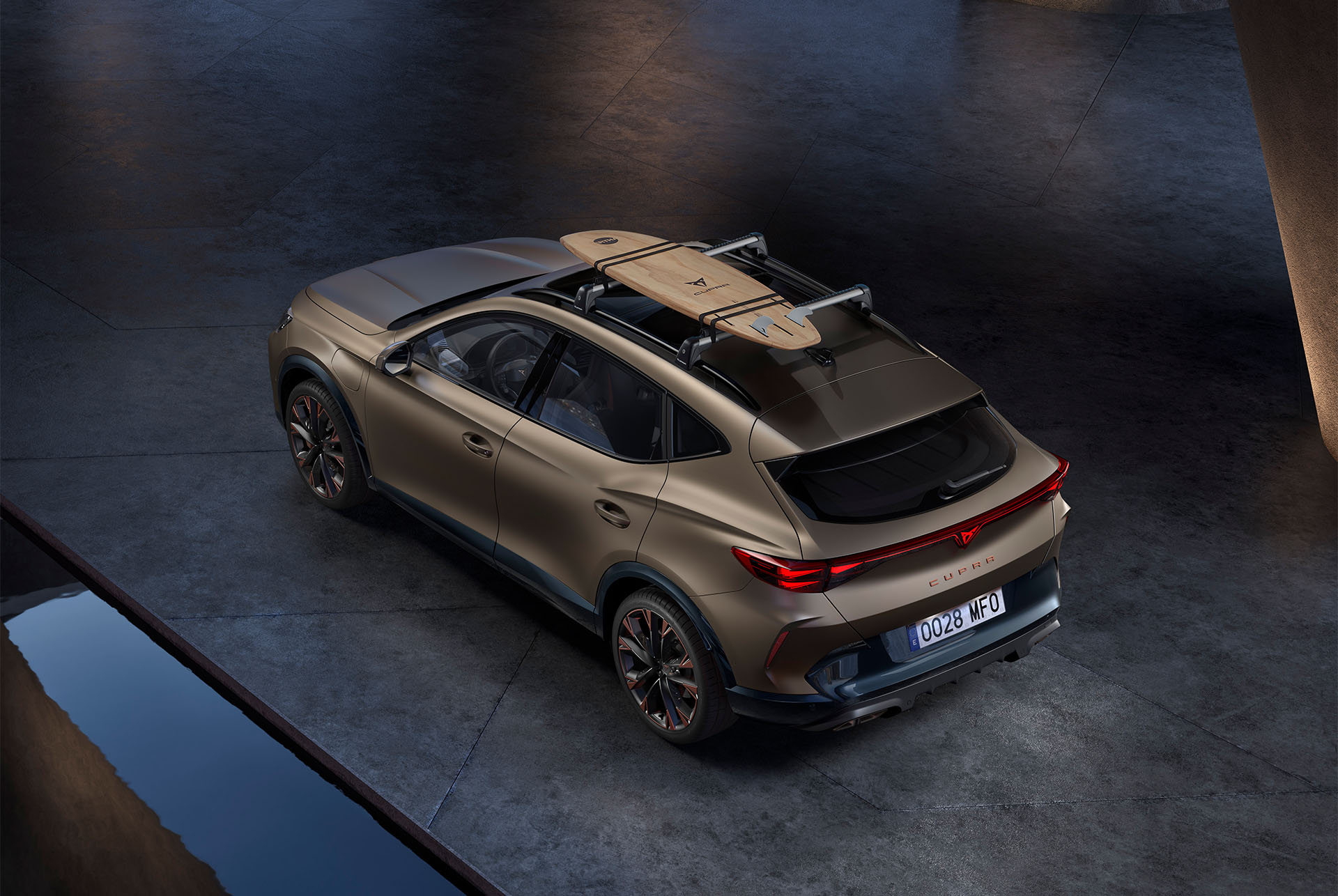 Bird’s eye view of new century bronze matt CUPRA Formentor 2024 with car roof surfboard rack accessory, car parked on concrete.