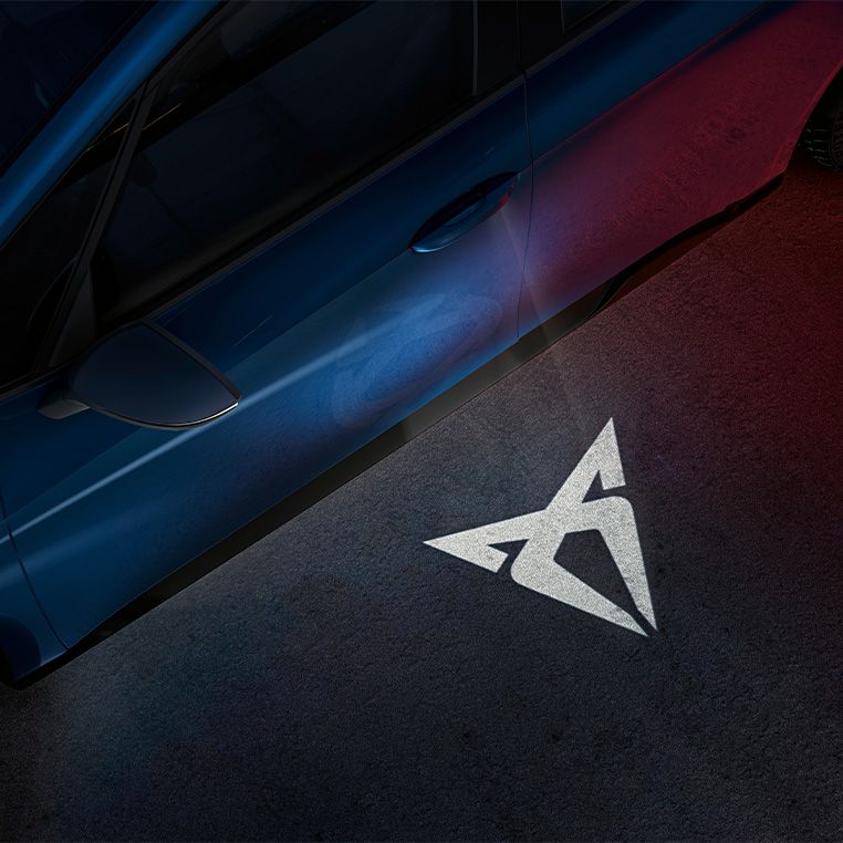 cupra car models’ welcome light with projected logo on pavement at night and cupra born electric vehicle in aurora blue close up